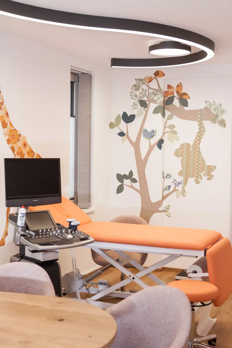 Untersuchungsliege vor Giraffe und Baum an der Wand