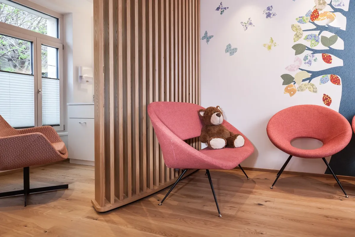 Wartebereich mit Holzlamellen und Teddybär im Sessel